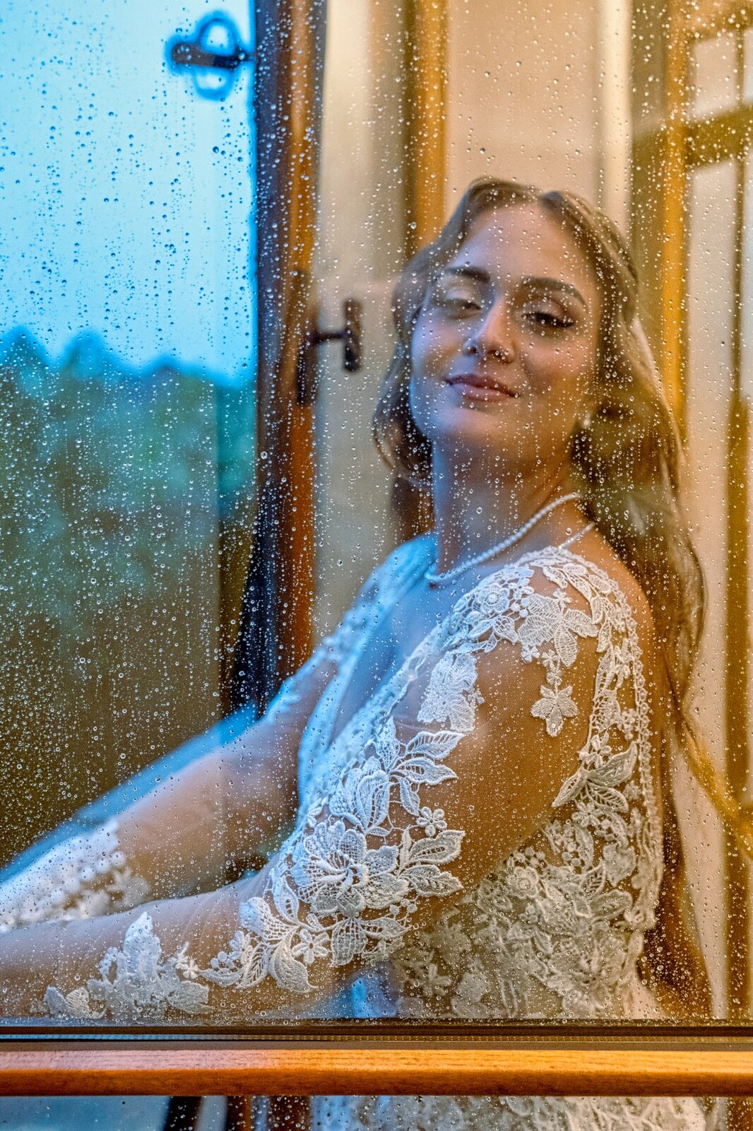 La sposa ritratta attraverso un vetro bagnato dalla pioggia